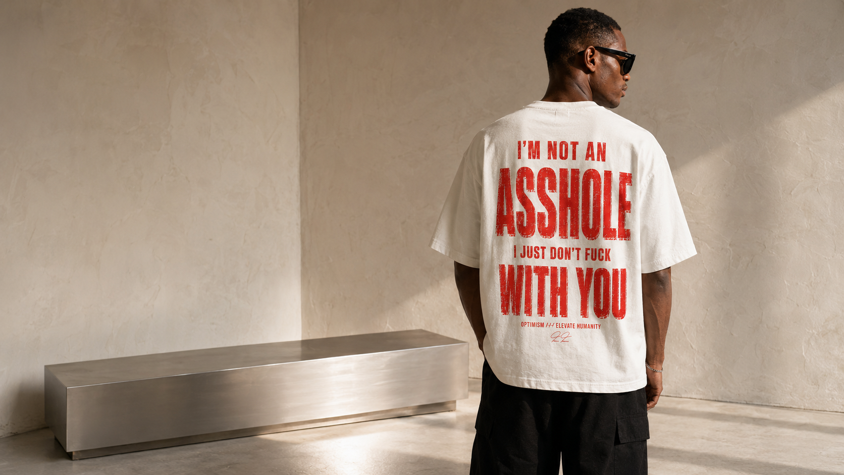 Adult male model wearing the bone-white OPTIMISM. Not for Everyone oversized tee from the back.