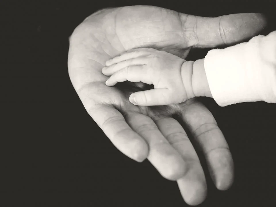 A child's hand resting in an adult's open palm