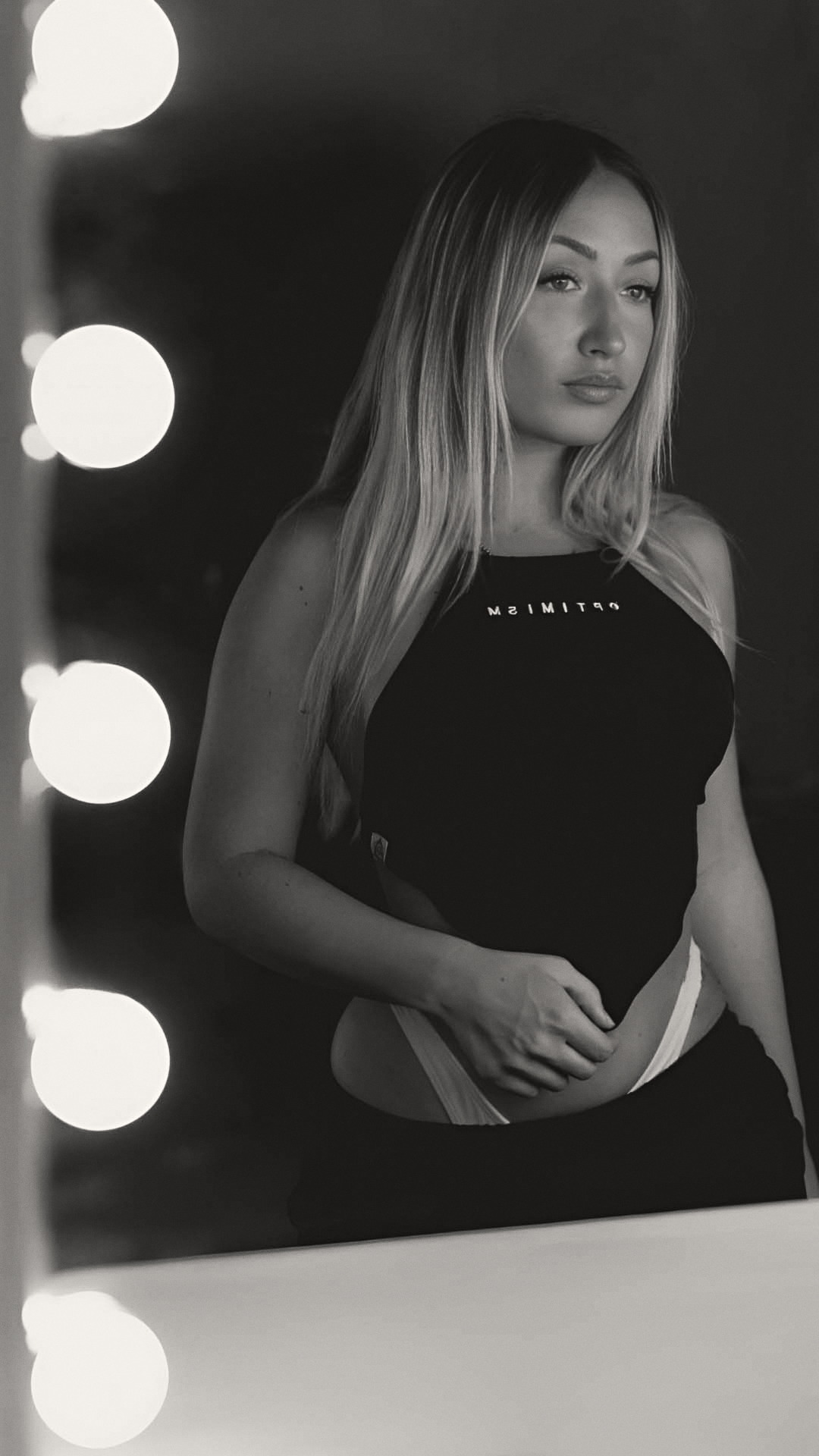 OPTIMISM. archive — Mirror portrait. Halter top under dressing-room light.