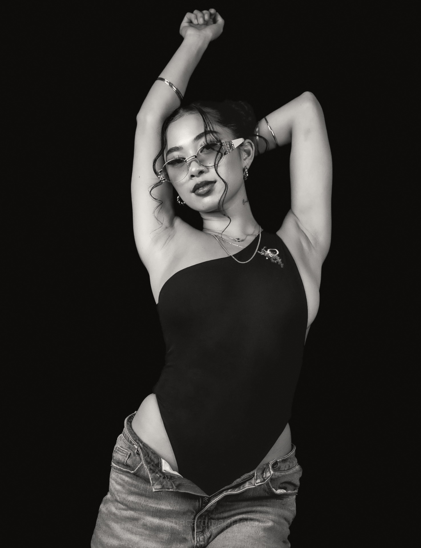 One-shoulder bodysuit. Emblem at the shoulder, black ground.